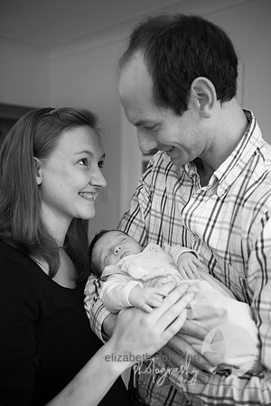 mum and dad looking at their baby girl Baby photo shoot in the home natural photography with little one family lifestyle swindon wiltshire