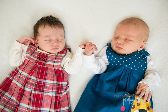 baby cousin girls lying together on a white blanket Baby photo shoot in the home natural photography with little one family lifestyle swindon wiltshire
