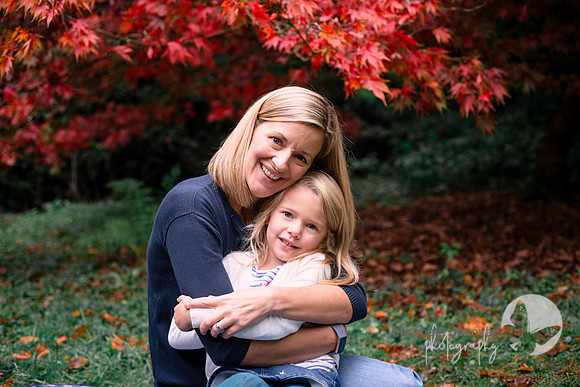 sweet mom and daughter cuddle in the autumn leaves elizabeth donovan photography outdoor photo shoot in the trees autumn