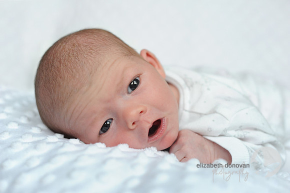 baby girl resting on a white blanket Baby photo shoot in the home natural photography with little one family lifestyle swindon wiltshire
