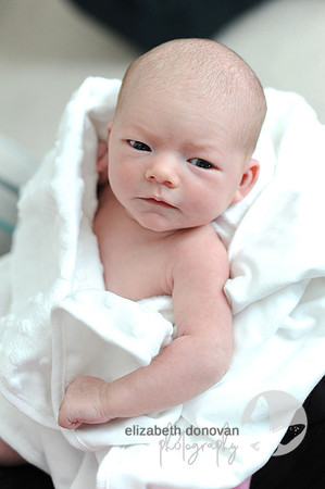 baby girl wrapped in white and looking at camera Baby photo shoot in the home natural photography with little one family lifestyle swindon wiltshire
